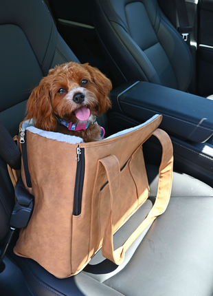 Dog in a brown pet seat carrier inside a car