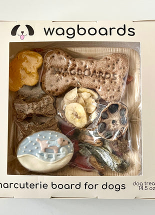 Wagboards charcuterie board for dogs with various treats in a clear window box.